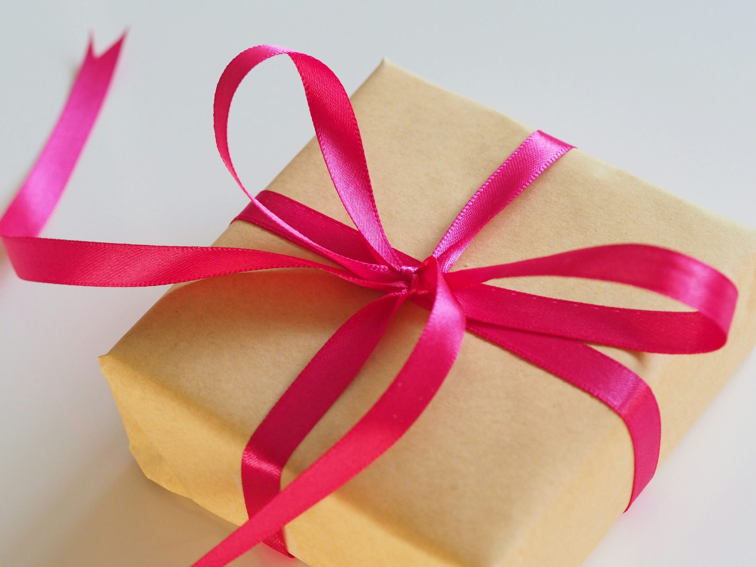 A small gift wrapped in brown paper and pink ribbon