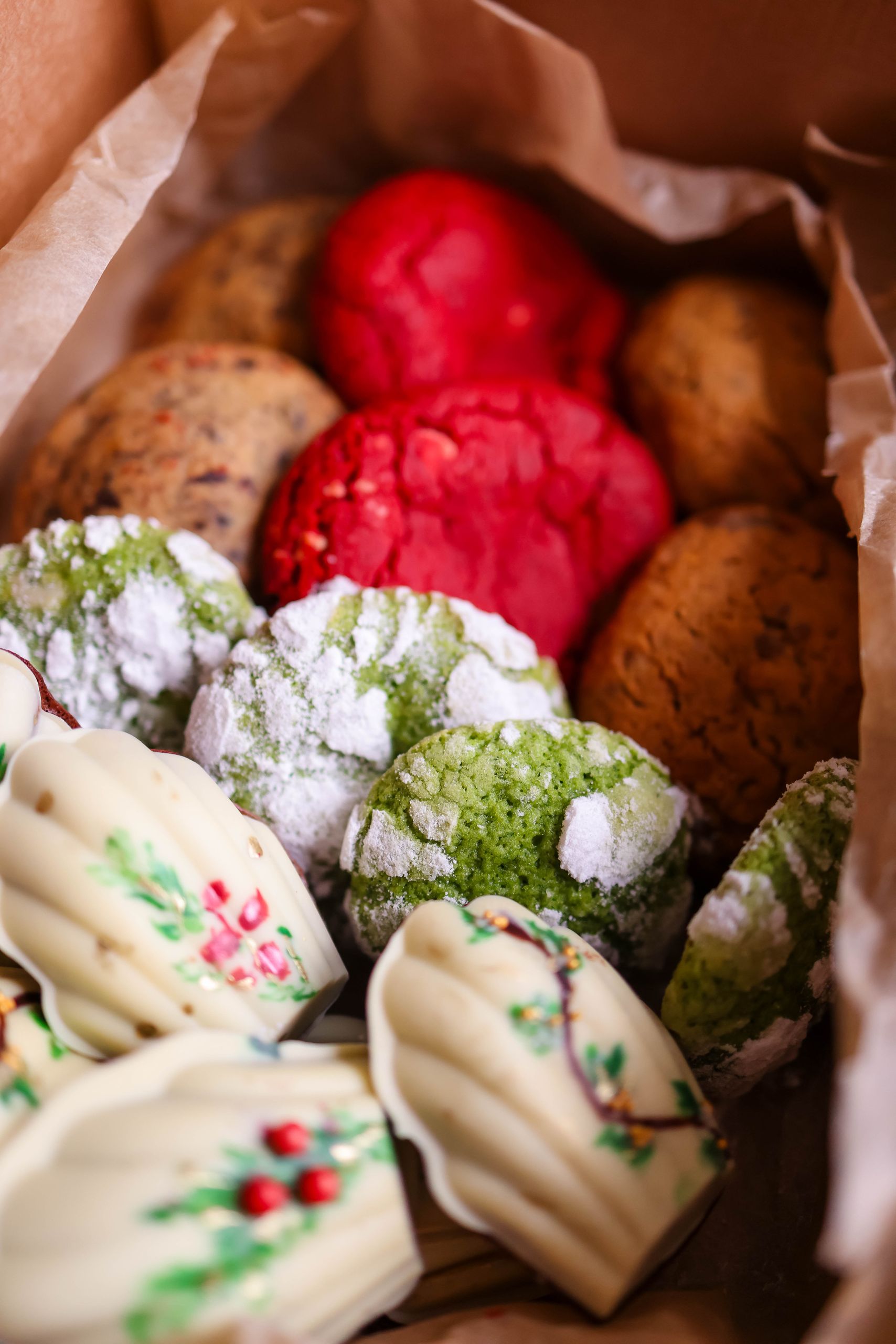 Colorful holiday cookies featuring various flavors and designs in a gift box.